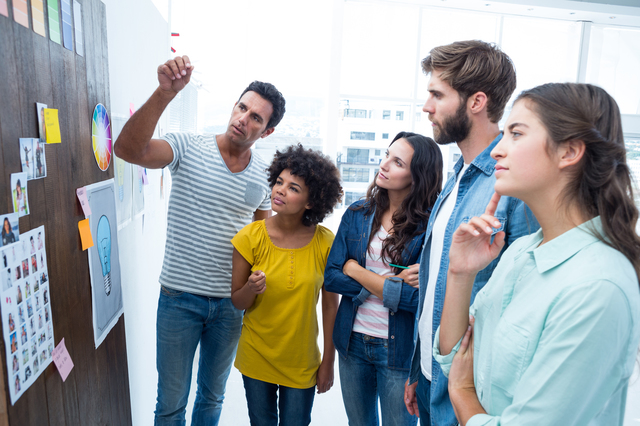 Young creative business people at work by blackboard at office